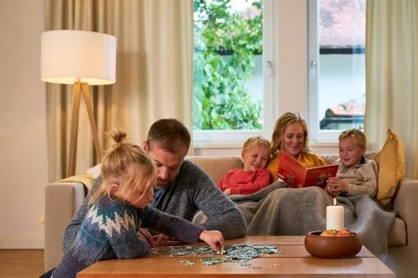 Familie mit drei Kindern sitzt gem&uuml;tlich im Wohnzimmer.