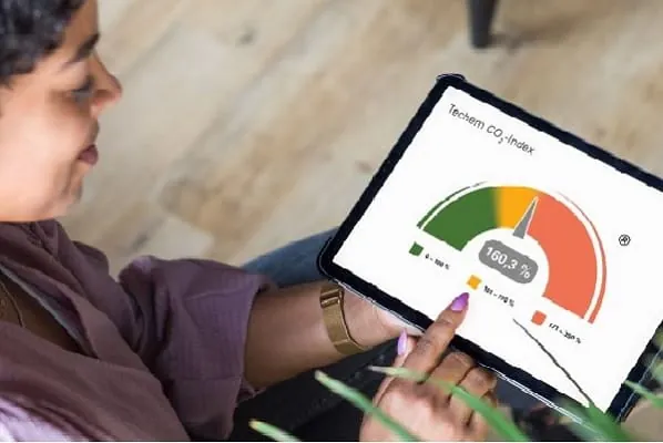 Frau schaut auf Tablet mit Grafik CO2-Index