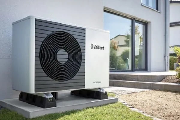 Weiße Luft-/Wasser-Wärmepumpe Monoblockbauweise von Vaillant vor Haus im Garten