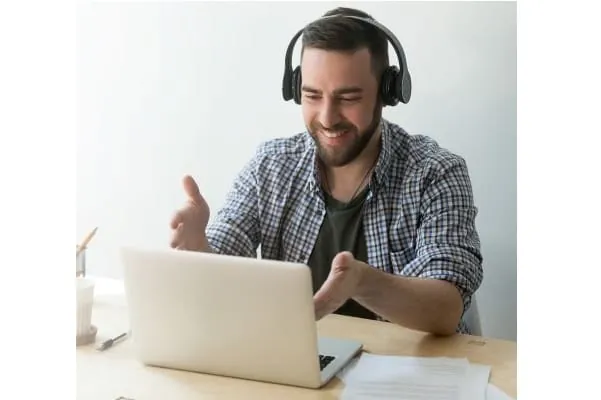 Mann lächelnd vor aufgeklappten Laptop