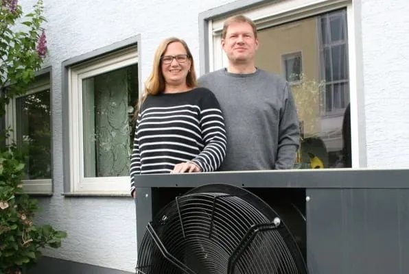 Mann und Frau stehen an ihrer Wärmepumpe vor ihren Einfamilienhaus.