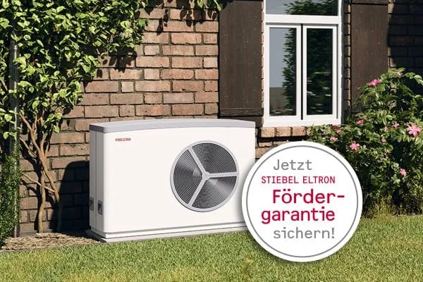 Au&szlig;eneinheit Luft-/Wasser-W&auml;rmepumpe vor verklinkerten Einfamilienhaus. Mit im Bild runde Grafik "Jetzt Stiebel Eltron F&ouml;rdergarantie sichern!"