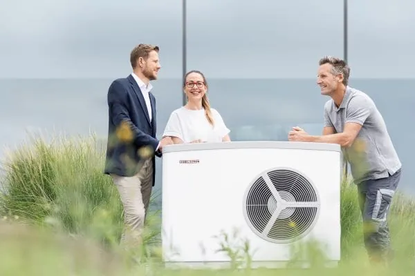 Mann und Frau und Heizungshandwerker stehen an einer W&auml;rmepumpe von Stiebel Eltron.