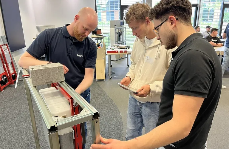 Philipp Hagedorn, Tece Außendienst, unterstützt die Auszubildenden bei der Installation einer Tecesolid WC-Betätigungsplatte.
