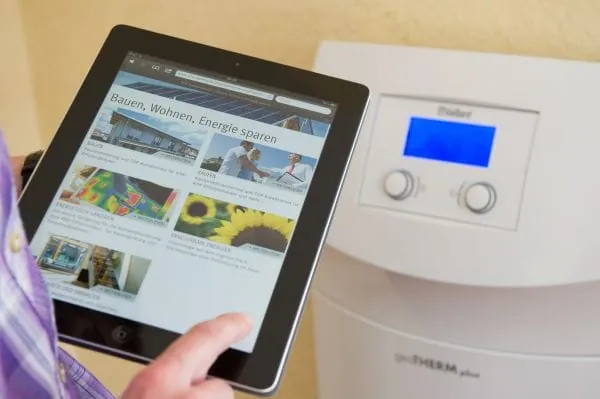 Person h&auml;lt Display vor Heizger&auml;t