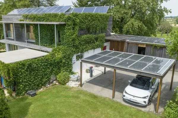 Begr&uuml;ntes Mehrfamilienhaus mit PV auf dem Dach, auf Nebengeb&auml;ude und Carport.
