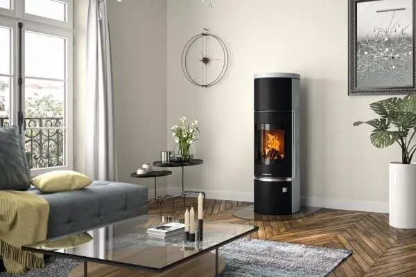 Holzkamin mit loderndem Holzfeuer hinter Glasscheibe im Wohnzimmer.