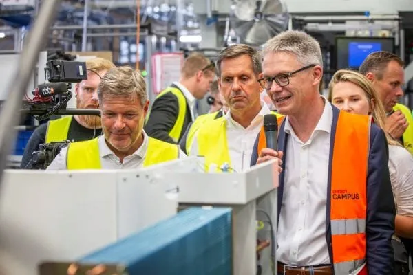 Vizekanzler Robert Habeck beim Werksbesuch Stiebel Eltron mit Niedersachsens Wirtschaftsminister Olaf Lies mit gelben Westen und CEO Kai Schiefelbein (orange Weste) an der Station „Verdrahtung und Isolierung“ in der Wärmepumpenproduktion. (v. l.)