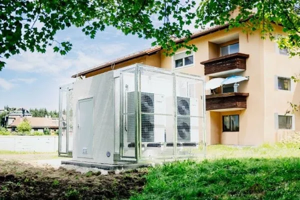 Containerl&ouml;sung Energiezentrale mit W&auml;rmepumpen vor einem Mehrfamilienhaus