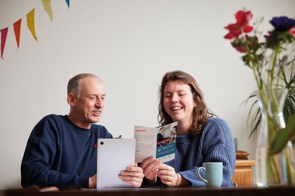 Mann und Frau sitzen am Tisch und schauen lachend in die Broschüre Heizspiegel