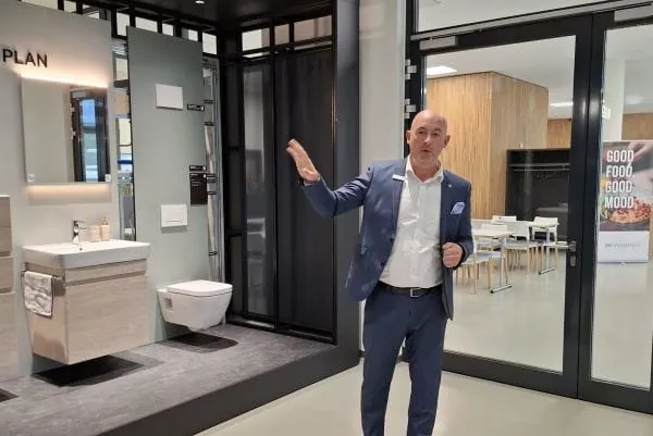 Geberit-Mitarbeiter vor Exponat Badserie im Foyer neues Verwaltungsgebäude.