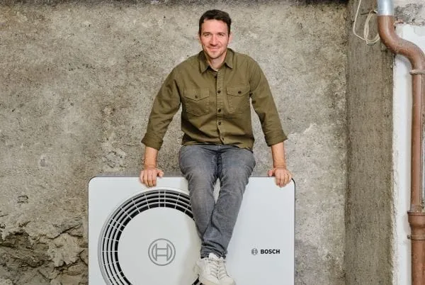 Skirennläufer Felix Neureuther sitzt auf einer weißen Wärmepumpe.