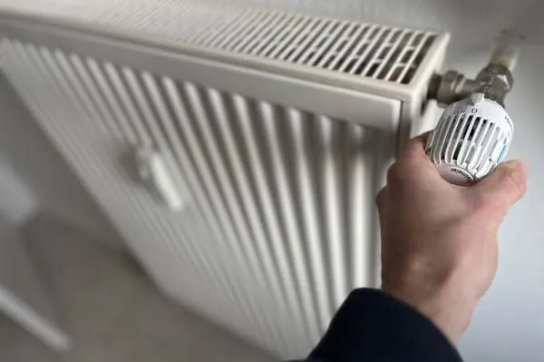 Hand dreht am Heizkörper-Thermostat