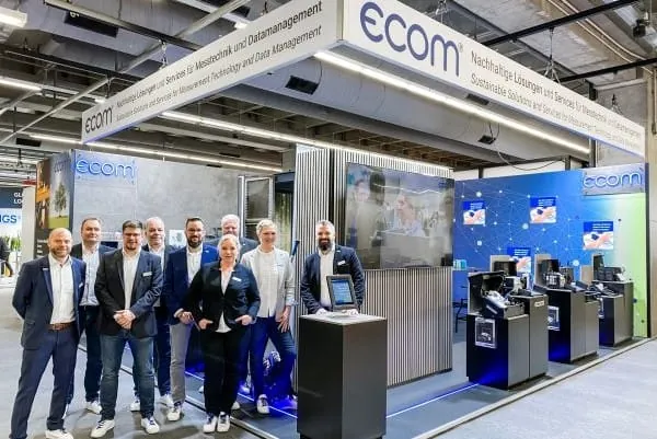 Neunk&ouml;pfiges Team von ecom vor Messestand.