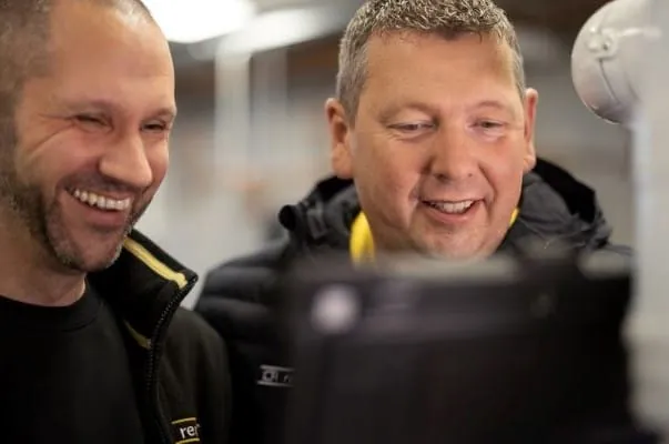 Zwei lachende Remeha-Mitarbeiter vor einem Heizger&auml;t.