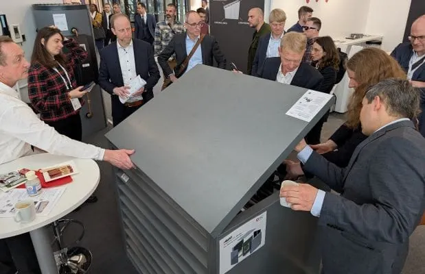 Messebesucher ISH umringen die Wärmepumpen-Schallschutzhaube von Atec auf der ISH. Ein Mitarbeiter öffnet halb die obere Klappe.