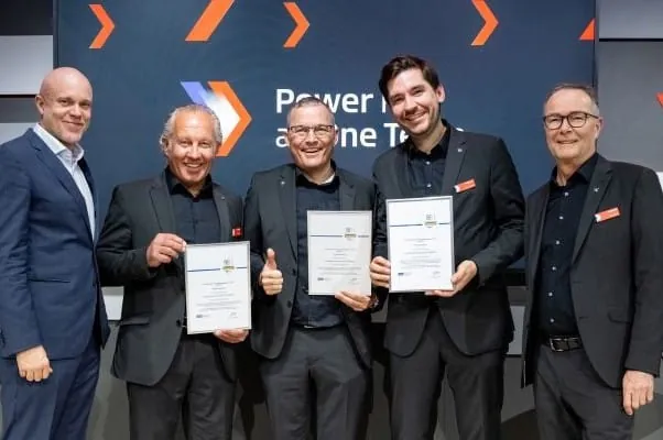 1 Mitarbeiter EUPD-Research und 4 Mitarbeiter von Viessmann in dunklen Anzugen auf dem Messestand Viessmann ISH, Drei halten die Urkunde zum SolarProsumer Award in den H&auml;nden vor den K&ouml;rper.