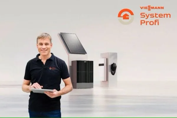 Handwerker steht mit IPad vor Produkten von Viessmann: PV-Modul, W&auml;rmepumpe, Stromspeicher und Ladebox. Produkte weit im Hintergrund.