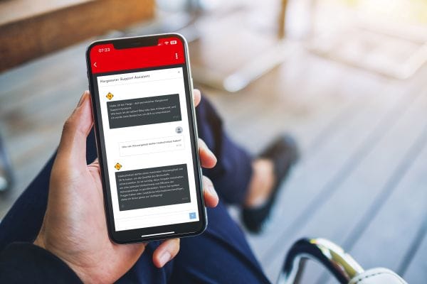 Frauenhand hält Handy mit Hargy-App auf dem Display