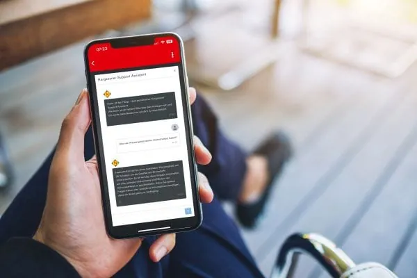 Frauenhand h&auml;lt Handy mit Hargy-App auf dem Display