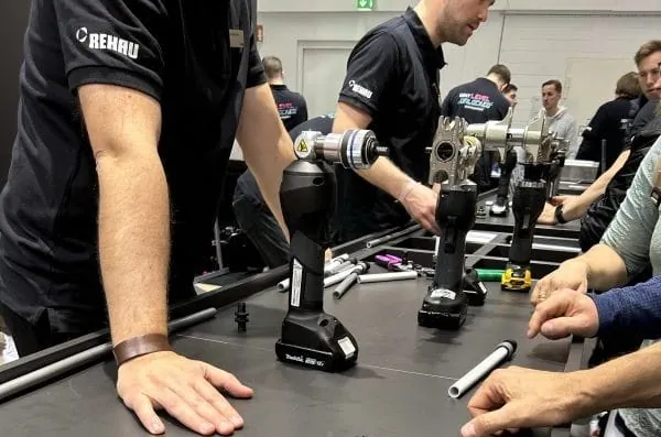 Rehau-Mitarbeiter an der Handwerkertheke auf dem Messestand ISH zeigen Handwerkern das Werkzeug Rautool f&uuml;r die Installation der Verbindungstechnik Schiebeh&uuml;lse f&uuml;r Rohrleitungen Trinkwasser/Heizung