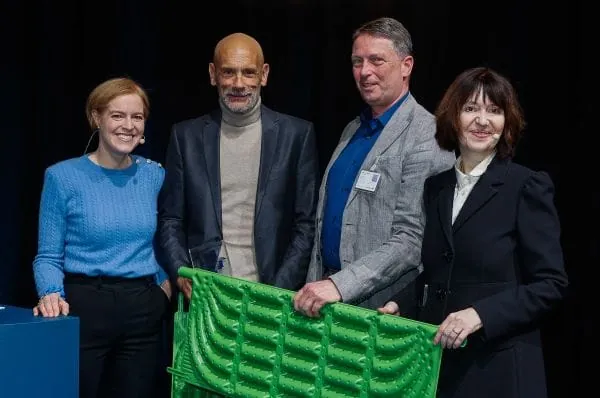 Zwei Frauen und zwei M&auml;nner halten den gr&uuml;nen Geolcollect-Absorber f&uuml;r Erdw&auml;rmepumpe in den H&auml;nden.