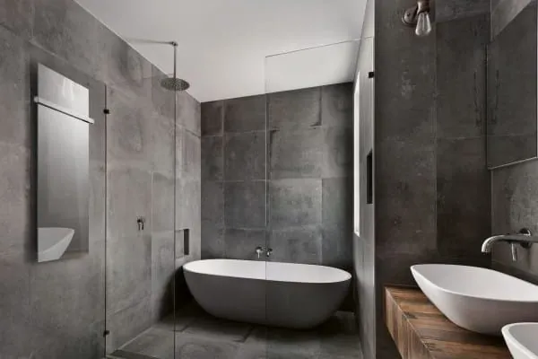 Metallicfarbenes Infrarot-Heizgerät an der Wand in einem Bad, das mit grauen Naturstein gefliest ist