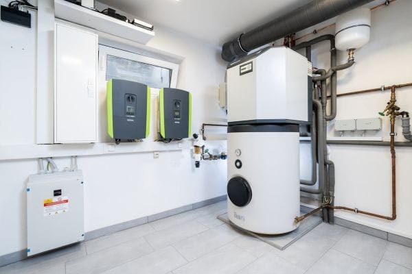 Keller Einfamilienhaus mit weißen Wänden. An der Wand zwei Wechselrichter, EMS. Daneben steht die Inneneinheit einer Wärmepumpe, angeschlossen an das Heizungssystem