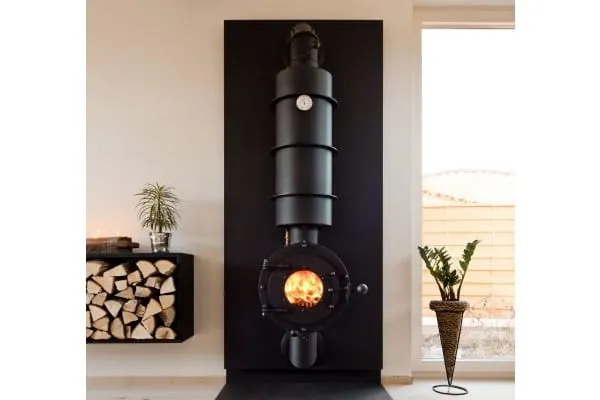schwarzer Holzscheitkamin mit Anschlusss an die Zentralheizung. Runde Feuerkammer mit runden Sichtfenster