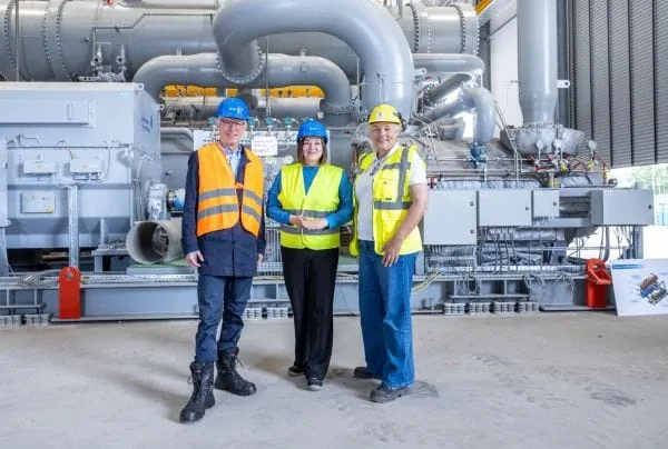 Delegation drei Personen mit Warnweste und Bauhelmen vpr Wärmepumpenaggregat