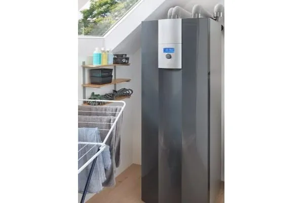 graue Erdw&auml;rmepumpe mit K&auml;ltemittel Propan im Dachgeschoss eines Einfamilienhauses. Vor dem schr&auml;gen Dachfenster neben dem Ger&auml;t ein Trockengestell mit aufgeh&auml;ngten Handt&uuml;chern.
