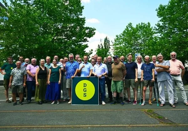 Gruppenbild 30 Teilnehmende Delegiertenversammlung DGS im Sommer 2025. Sie stehen auf einem Parkplatz im Hintergrund Bäume