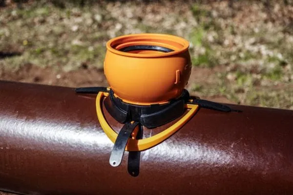 Dunkelbraunes Steinzeurohr mit aufmontierten Anschluss aus orangem Kunststoffrohr f&uuml;r Abwasser