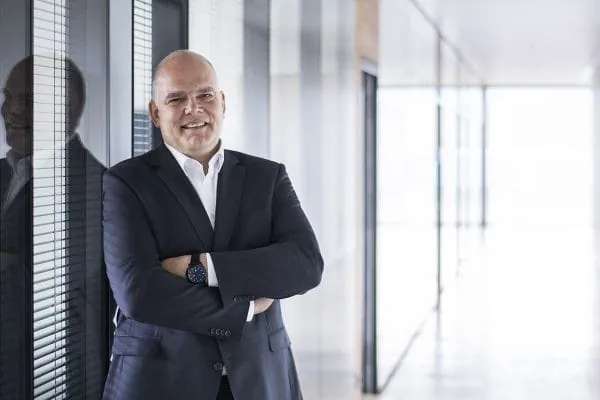 Portr&auml;tfoto Burkhard Max, Gesch&auml;ftsf&uuml;hrer der Stiebel Eltron Deutschland Vertriebsgesellschaft im dunklen Anzug, wei&szlig;es Hemd an eine Fensterfront gelehnt