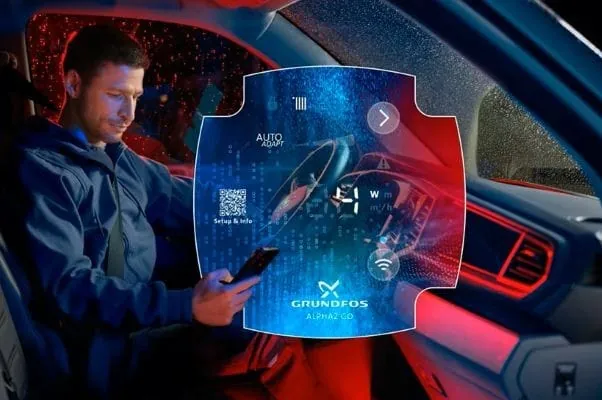 Installateur im Firmen-Transporter mit Hnandy und der Alpha-Go-App auf der Anzeige