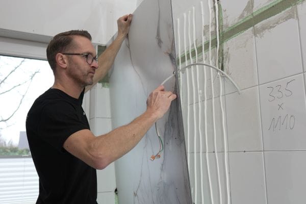 Schnell angeklebt statt lange Trocknungszeiten – mit hochwertigen Wandverkleidungen wie RenoDeco werden aufwendige Fliesenarbeiten umgangen.