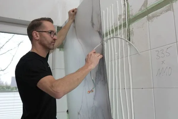 Schnell angeklebt statt lange Trocknungszeiten – mit hochwertigen Wandverkleidungen wie RenoDeco werden aufwendige Fliesenarbeiten umgangen.