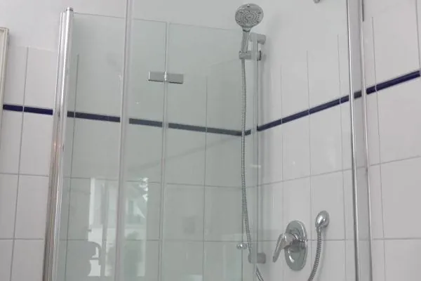 Vorher: Kalte weiße Fliesen, viele Fugen, ein hoher Einstieg in die Dusche und eine Ausstattung, die deutlich in die Jahre gekommen ist ...