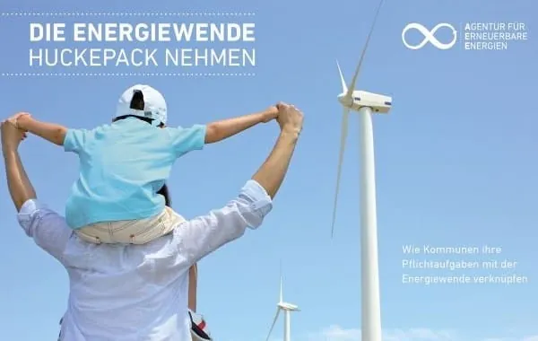 Kind Huckepack auf Schultern vom Vater , im Hintergrund Widnräder und blauer Himmel