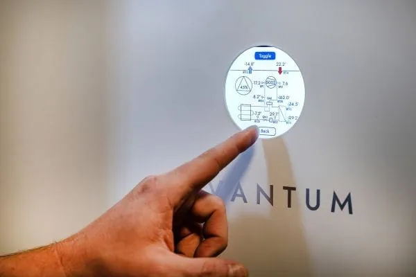 Zeigefinger tippt auf das digitale Bedienfeld einer Abluftwärmepumpe