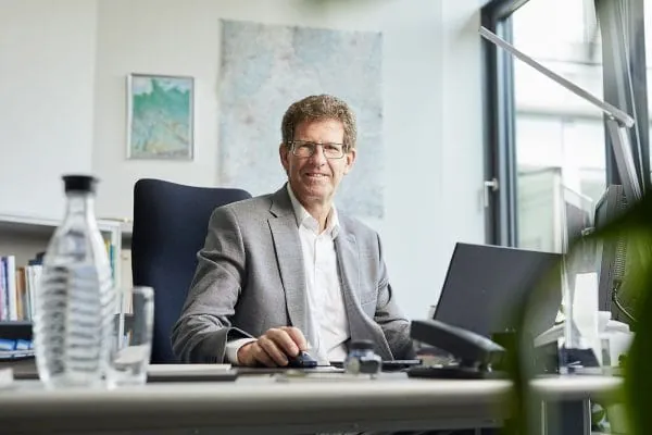 Dr. Volker Kienzlen sitzt am Schreibtisch und lächelt.