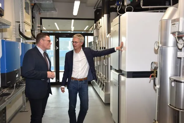 Wilhelm Gebhard im Gespräch mit Dr. Kai Schiefelbein an den beiden Wärmepumpen, die im Energy Campus für Heizung, Kühlung und Warmwasserbereitung sorgen (v. l.).