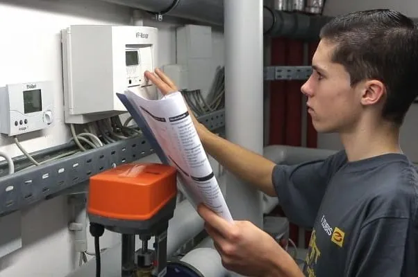 m&auml;nnlicher Auszubildender Elektriker vor Energiemanagementsystem W&auml;rmepumpe