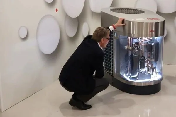 Bundestagsabgeorneter CDU in der Hocke vor einem Modell W&auml;rmepumpe mit Sichfenster