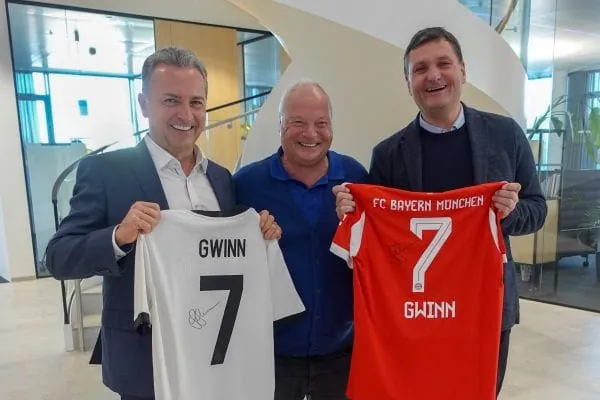 Roland Benkeser (Mitte) freut sich &uuml;ber die Spende f&uuml;r den Smile and Help e.V. Als Dankesch&ouml;n &uuml;bergibt der ehemalige Kessel-Mitarbeiter ein signiertes Deutschlandtrikot der Projektbotschafterin und Fu&szlig;ball-Nationalspielerin Giulia Gwinn an den Vorstandsvorsitzenden Stefan Grenzebach (links) und ein FC Bayern-Trikot an Vorstand Alexander Kessel (rechts).