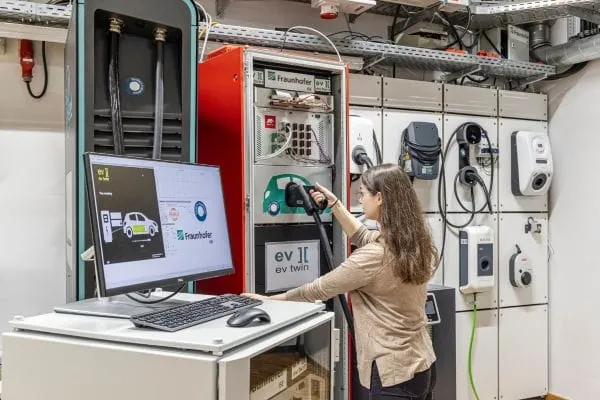 Forscherin vor Teststand im Digital Grid Lap testet am digitalen Zwilling Wallboxen und solares Laden