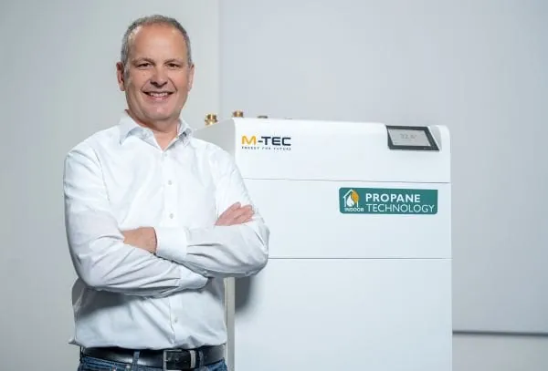 GF von M-TEC Peter Huemer neben neuer Innenraum-Propan-Wärmepumpe