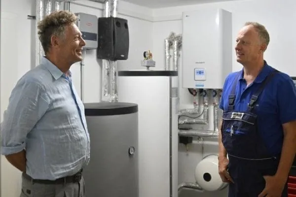 Kunde und Heizungsbauer im Heizungskeller vor Anlage