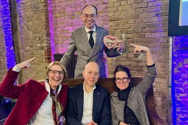 4 Personen, drei sitzend freuen sich.