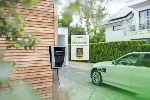 Wallbox an Hauswand, daneben E-Auto verbunden mit Ladekabel